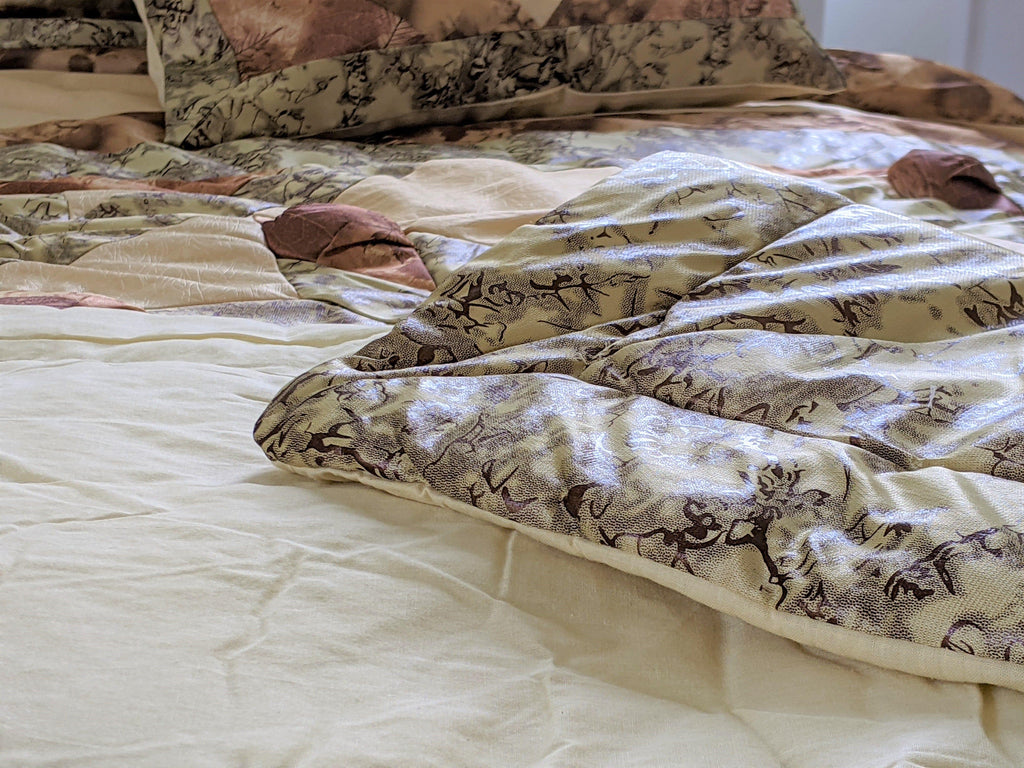 Close-up of comforter bed surface with beige, green, and brown camo-style print