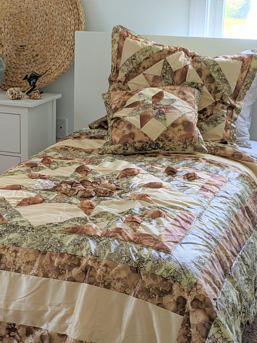 Quilted comforter and two matching pillows in earthy beige, brown, and green patchwork