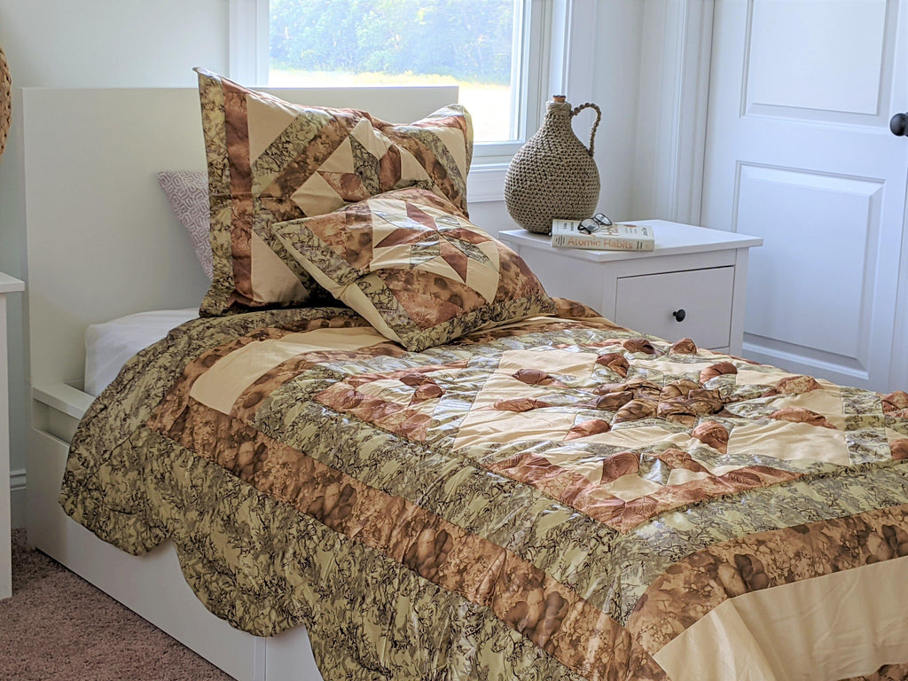 Beige, brown, and green quilted comforter with patchwork squares and two matching pillows