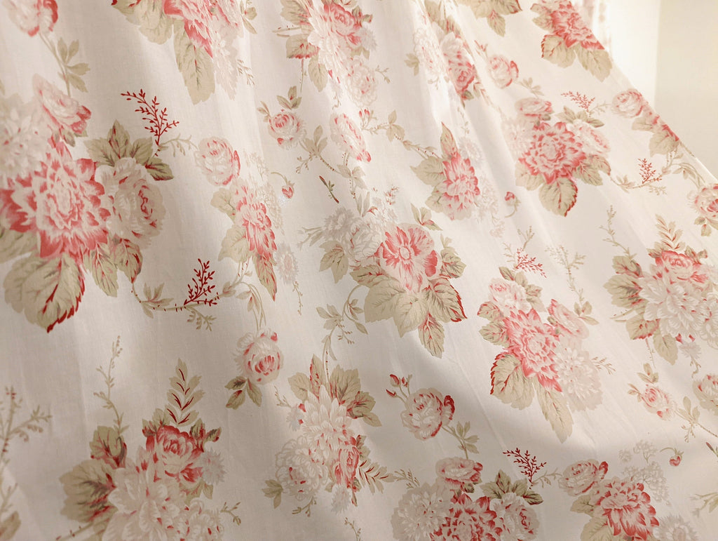 Close-up of sheer cream curtain fabric with pink rose and green leaf floral print