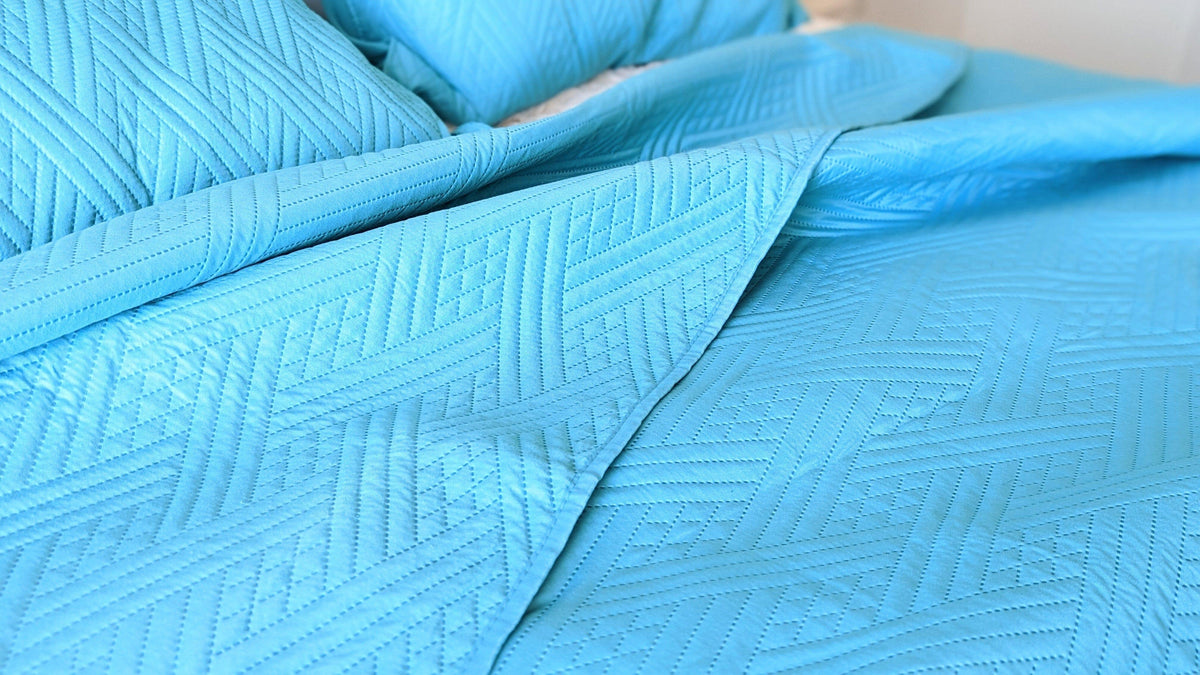 Close-up of turquoise teal quilted bedspread with raised wave stitch texture