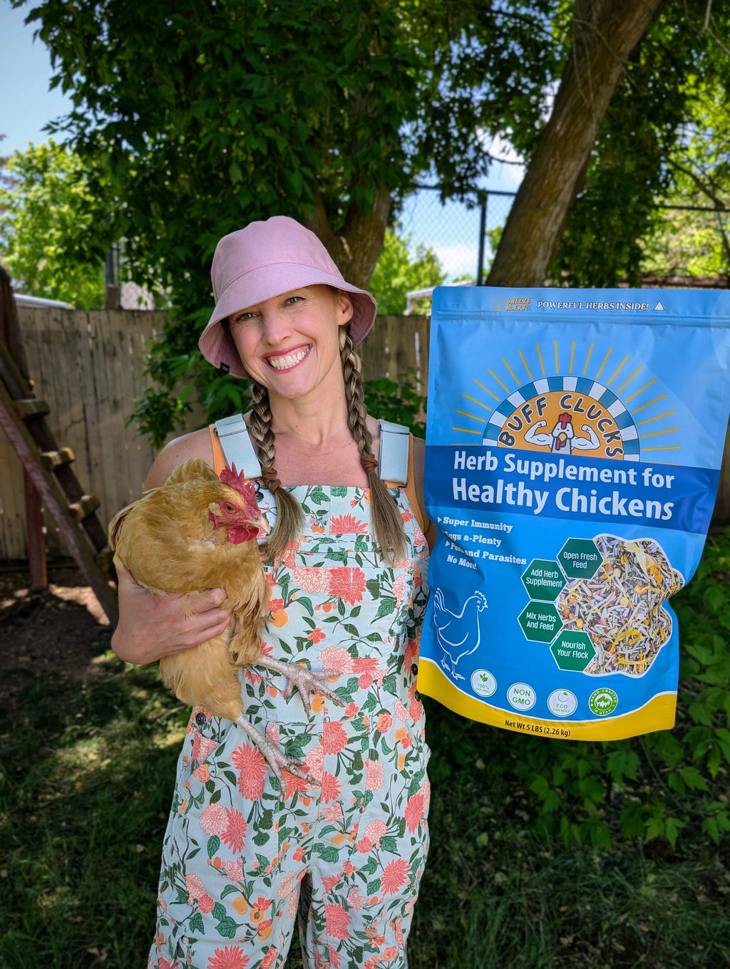 Blue herb supplement pouch held with a hen in an outdoor yard