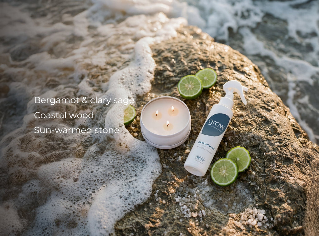 Small white 3-wick candle with three flames on rocky shore with citrus and spray bottle