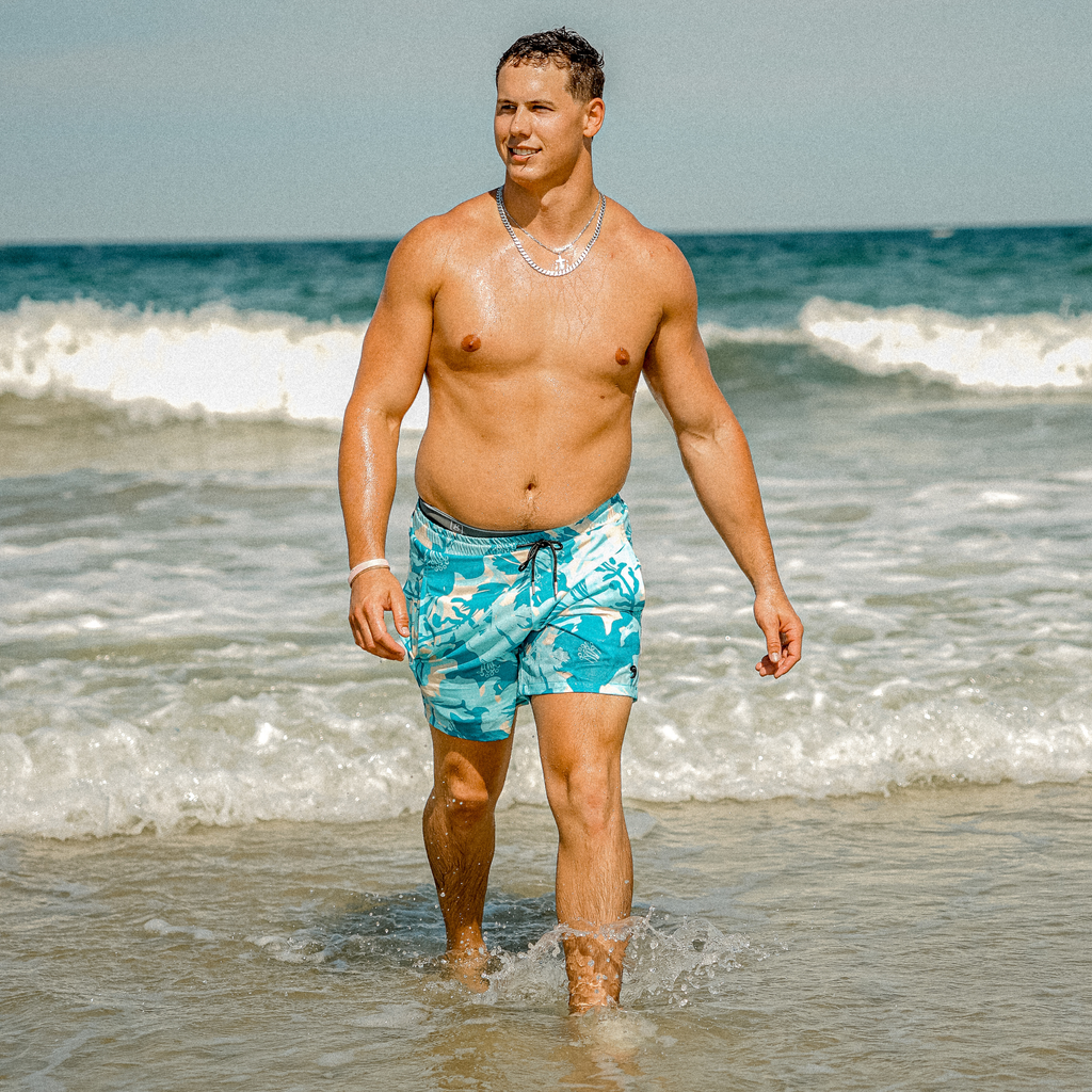 Turquoise camo swim shorts with elastic waistband and black drawstring, worn in water