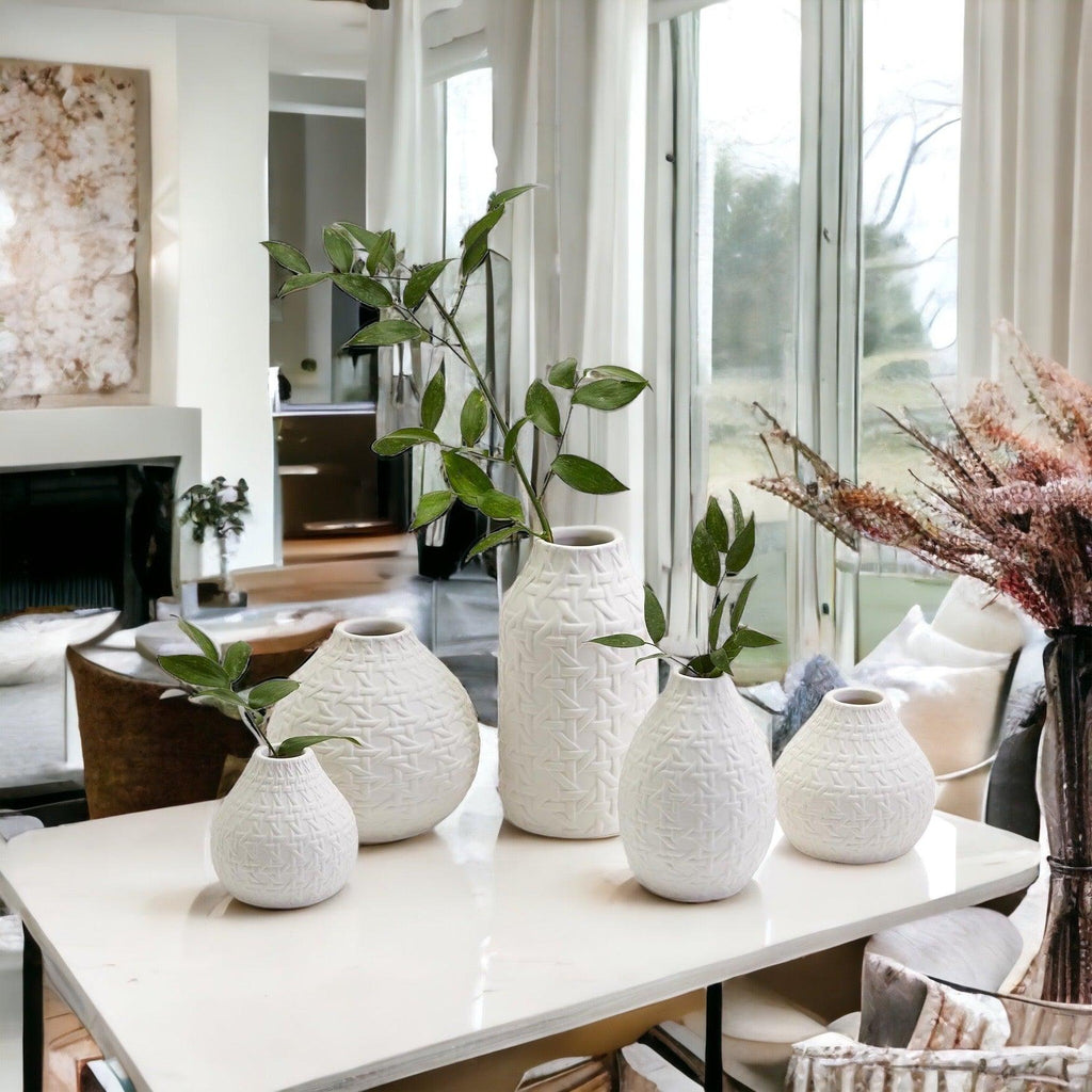 White textured web-pattern vases with green stems displayed on a table