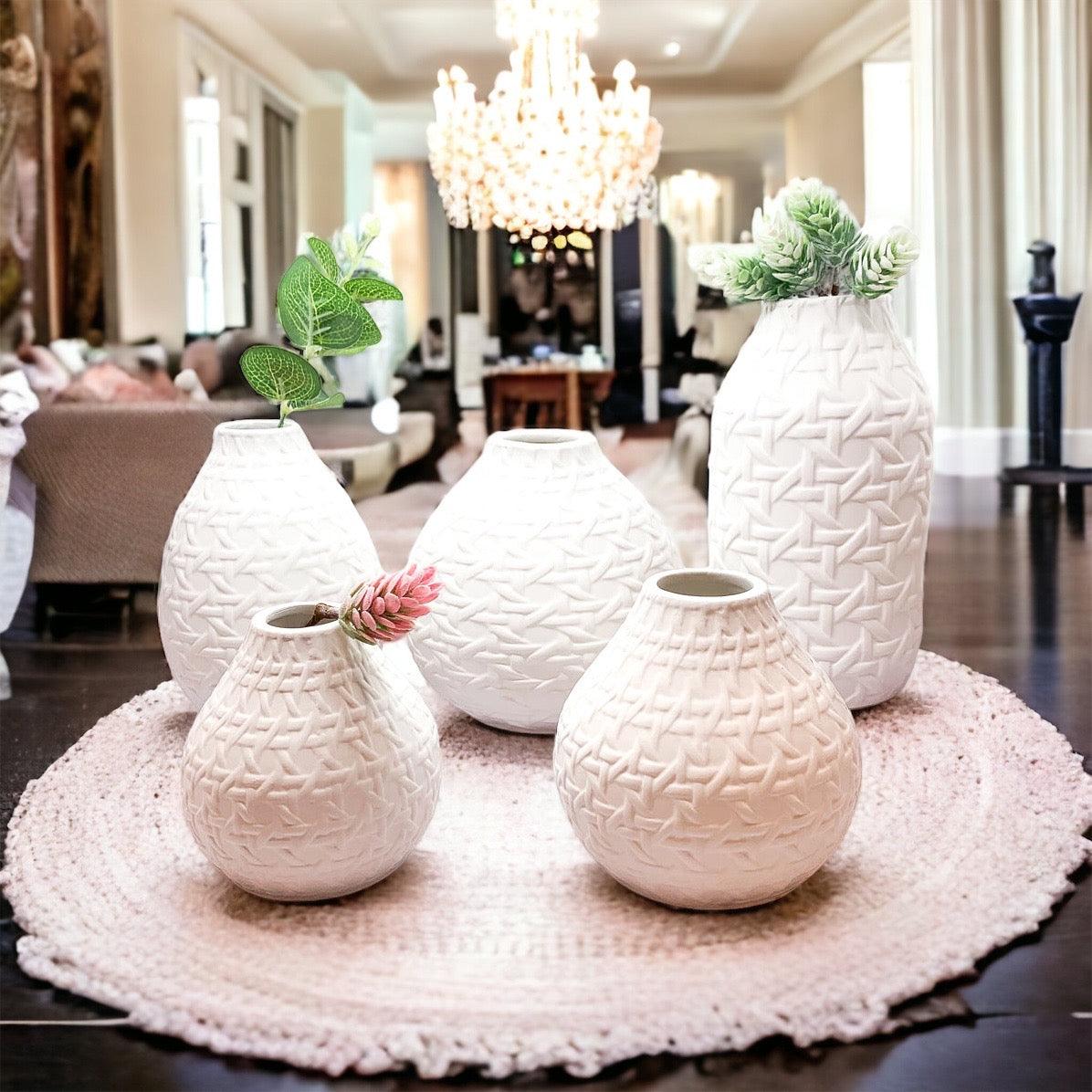 White web-pattern vases with green stems, arranged on a round rug