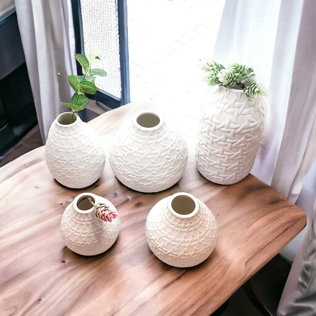 Five white web-pattern vases with open tops, arranged on a wooden surface