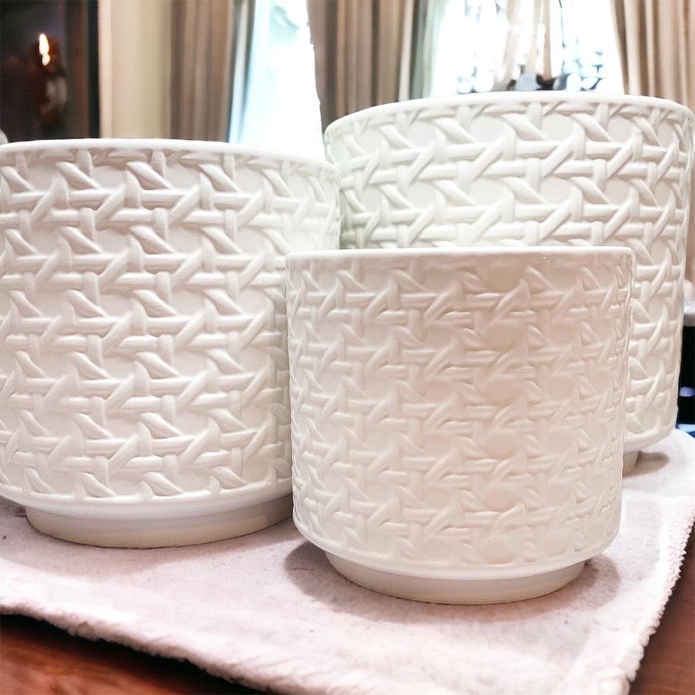 Close-up of white woven web-pattern vases with open tops