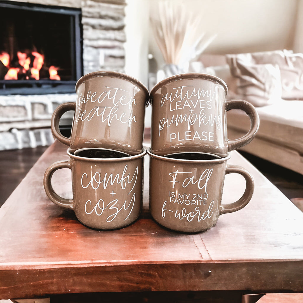 Set of four brown ceramic coffee mugs with white fall-themed printed lettering