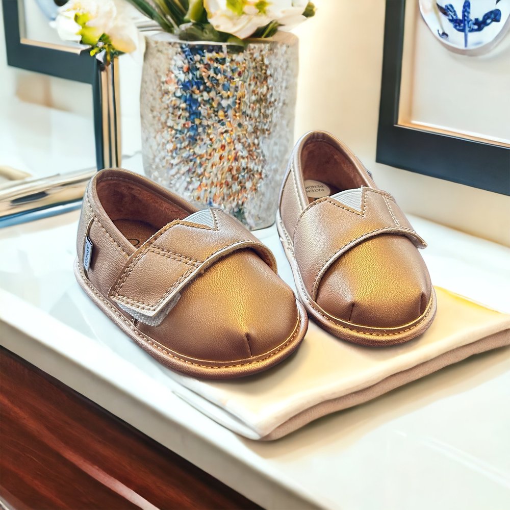 Gold metallic slip-on shoe topper pair with padded straps and stitched details
