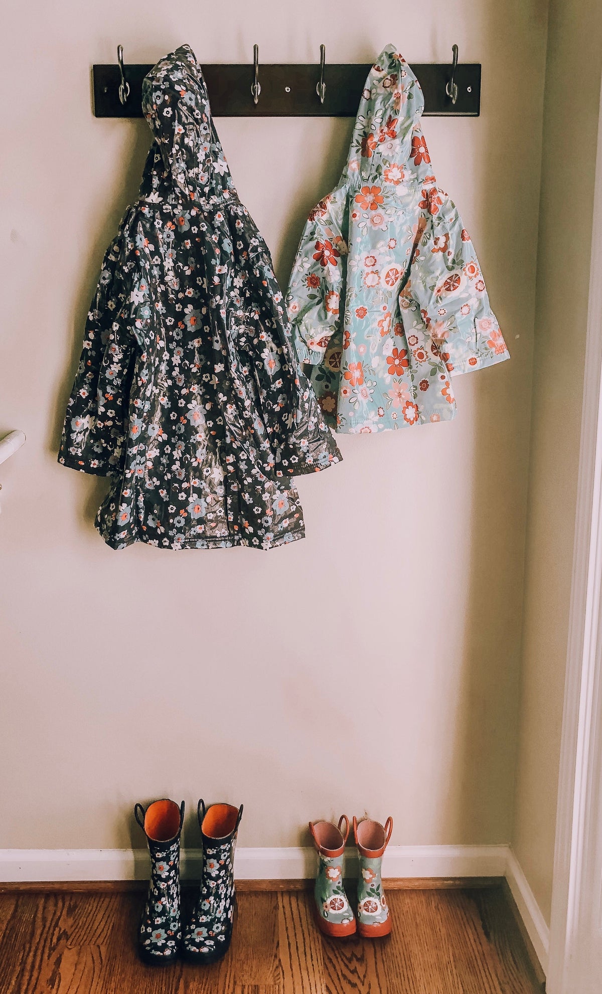 Hanging kids rain boots with teal floral print and red trim on wall hooks