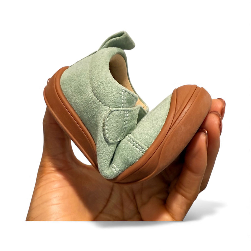 Kids mint-green suede barefoot sneaker held in hand, brown rubber sole