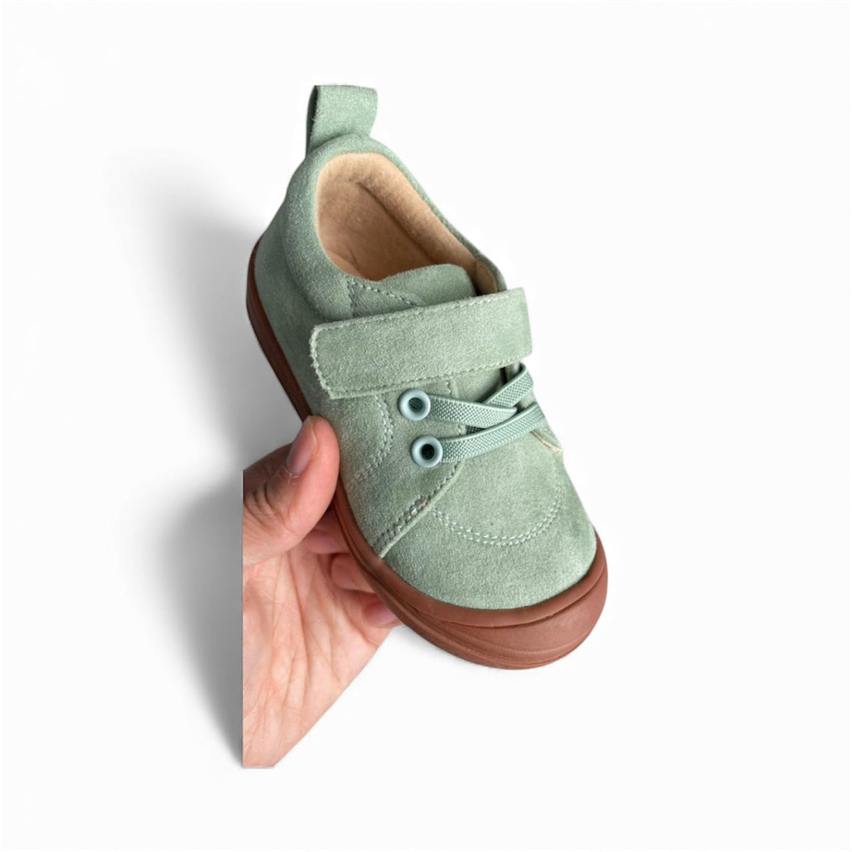 Kids mint suede barefoot sneakers with Velcro strap, hand-held close-up