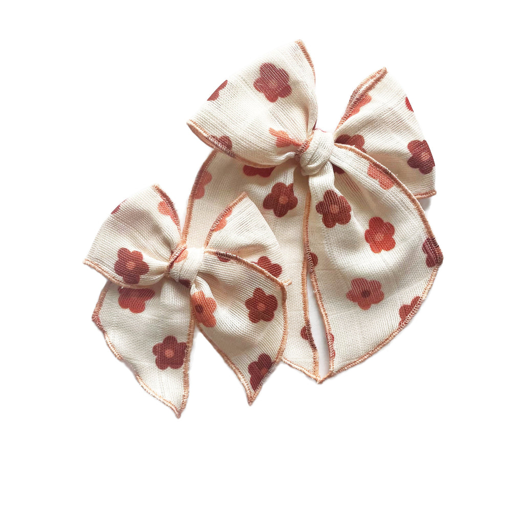 Cream gauze bow with red clover daisy print and stitched edges, center knot tie