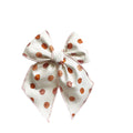 Cream fabric hair bow with pumpkin-pattern print and tied center knot