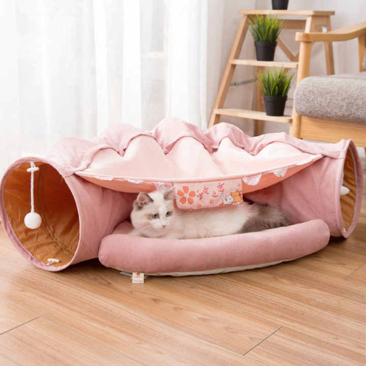 Collapsible cat tunnel tube with removable cat bed, pink fabric and beige cushion, cat inside