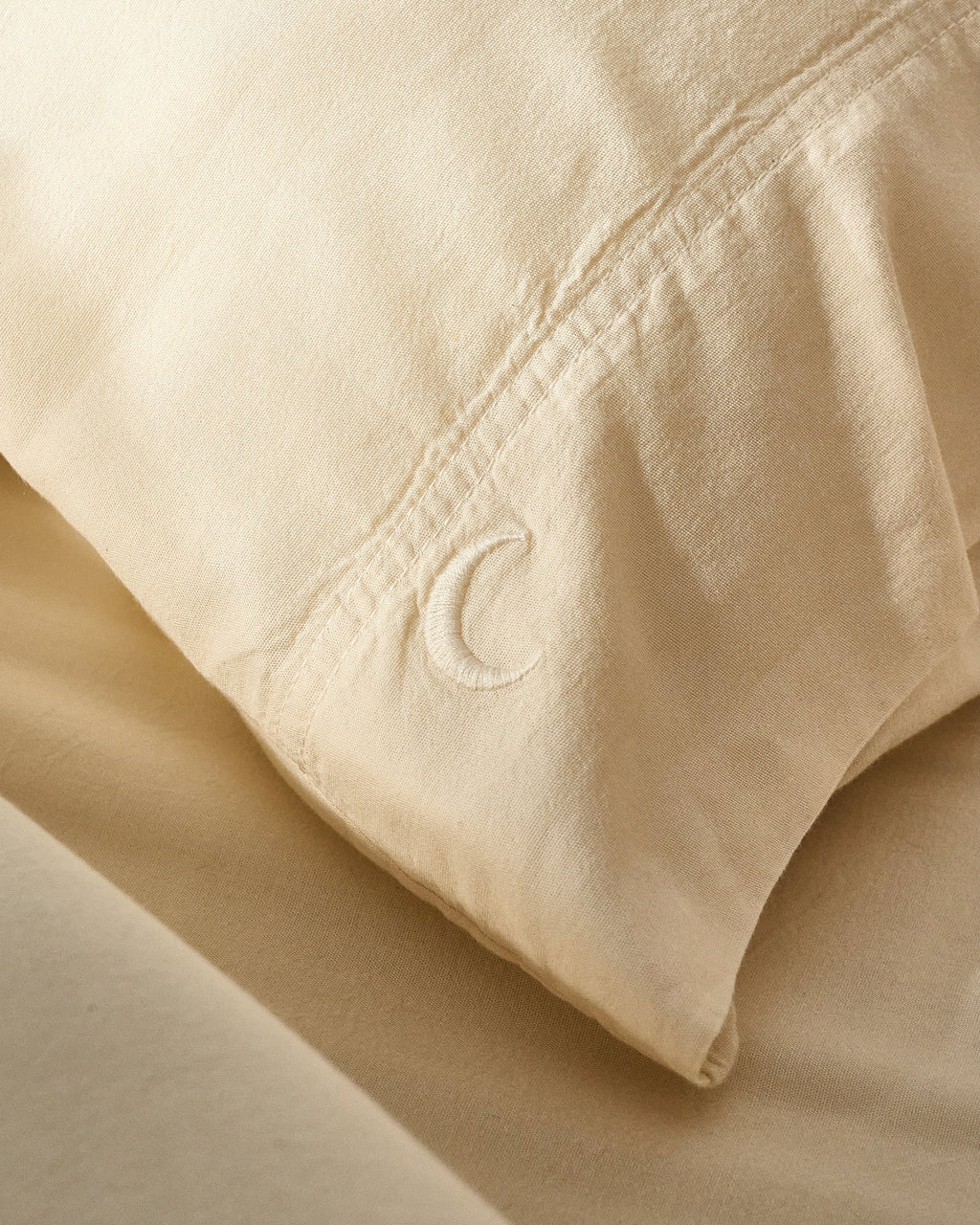 Cream pillowcase set close-up of fabric with small embroidered C on corner