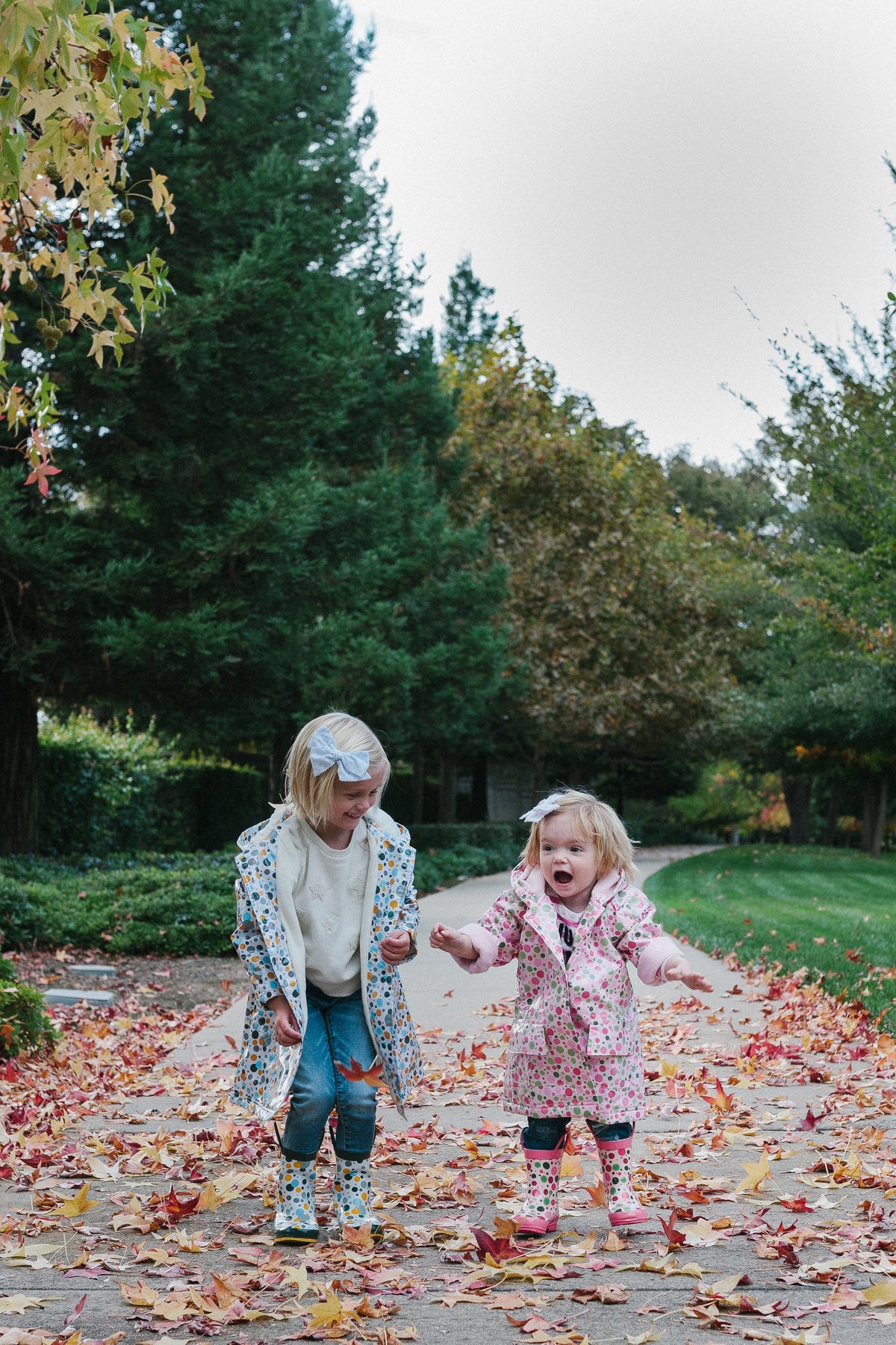 Child wearing white multicolor dot rain boots with dark green upper and yellow sole