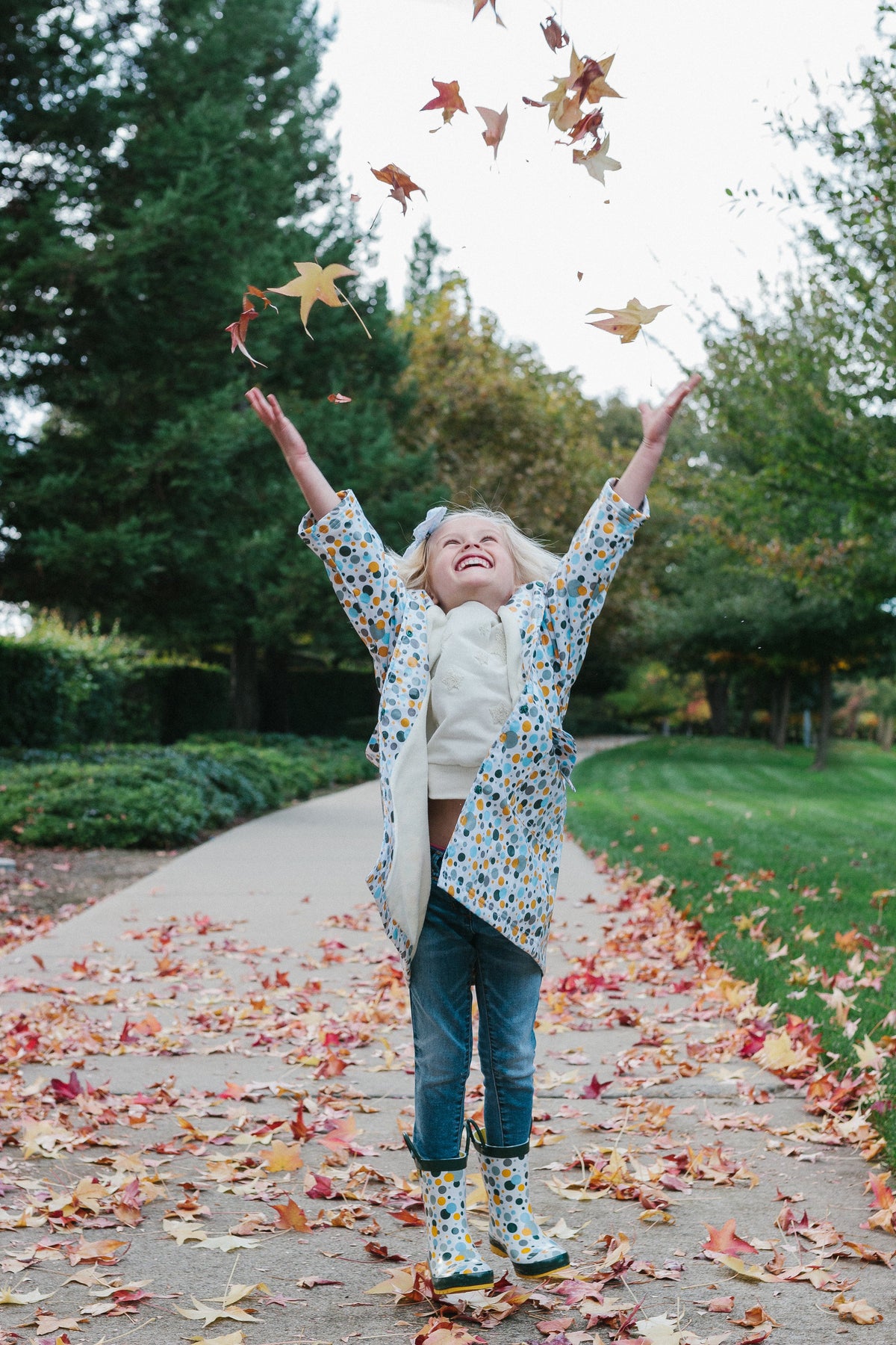 Kids wearing white multicolor dot rain boots with dark green tops