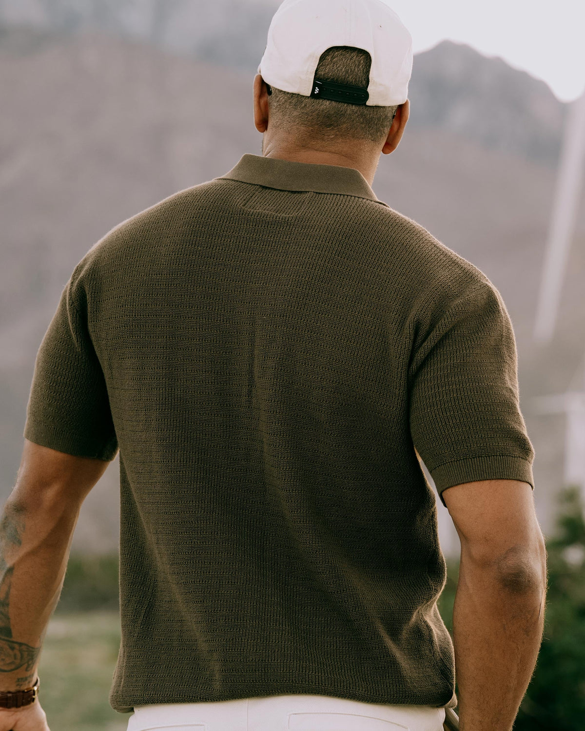Men's dark-brown knit golf polo, short sleeves and collared back view.