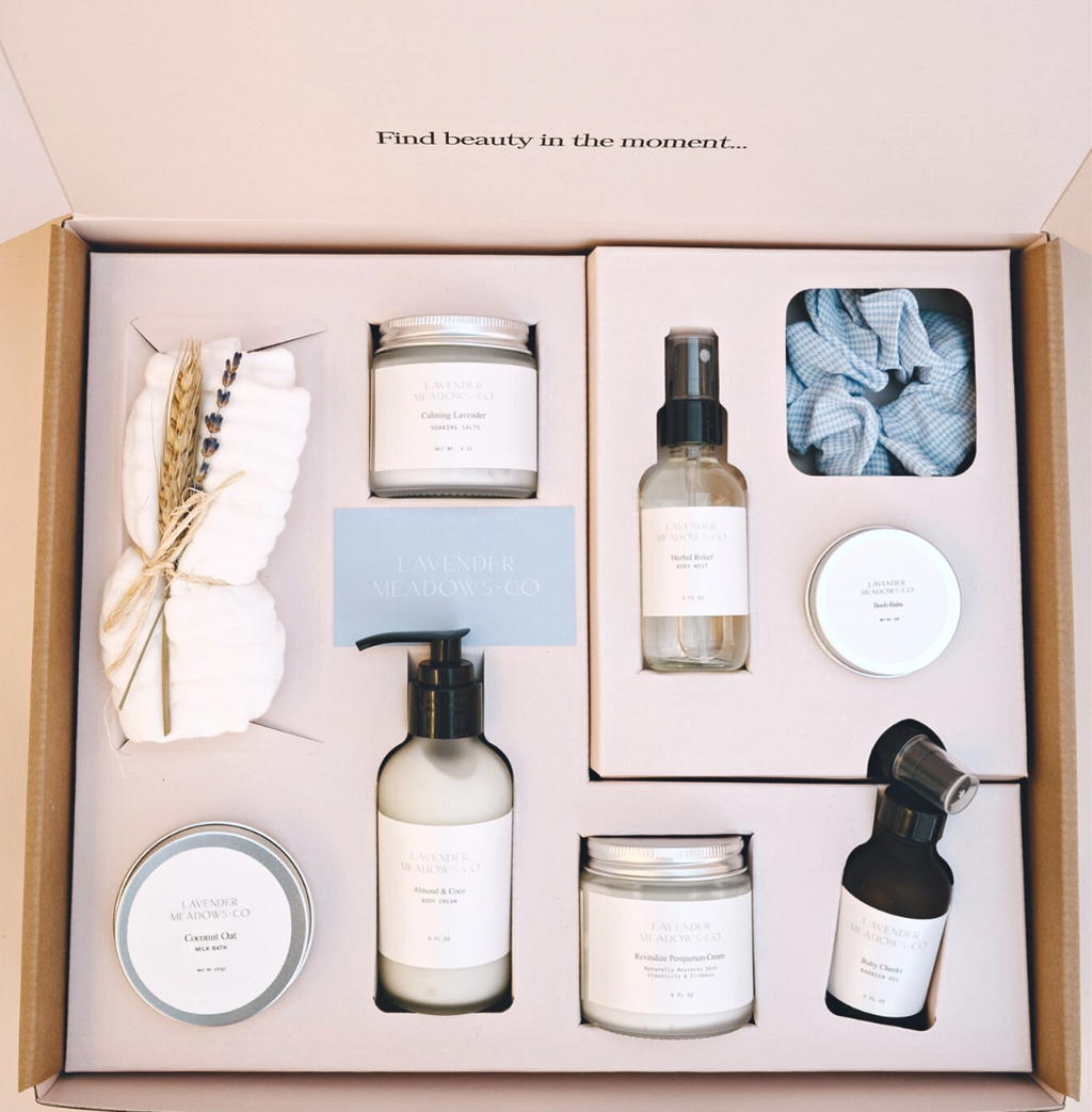 Lavender Meadows Co postpartum care package box with bottles, tins, and wrapped muslin cloth
