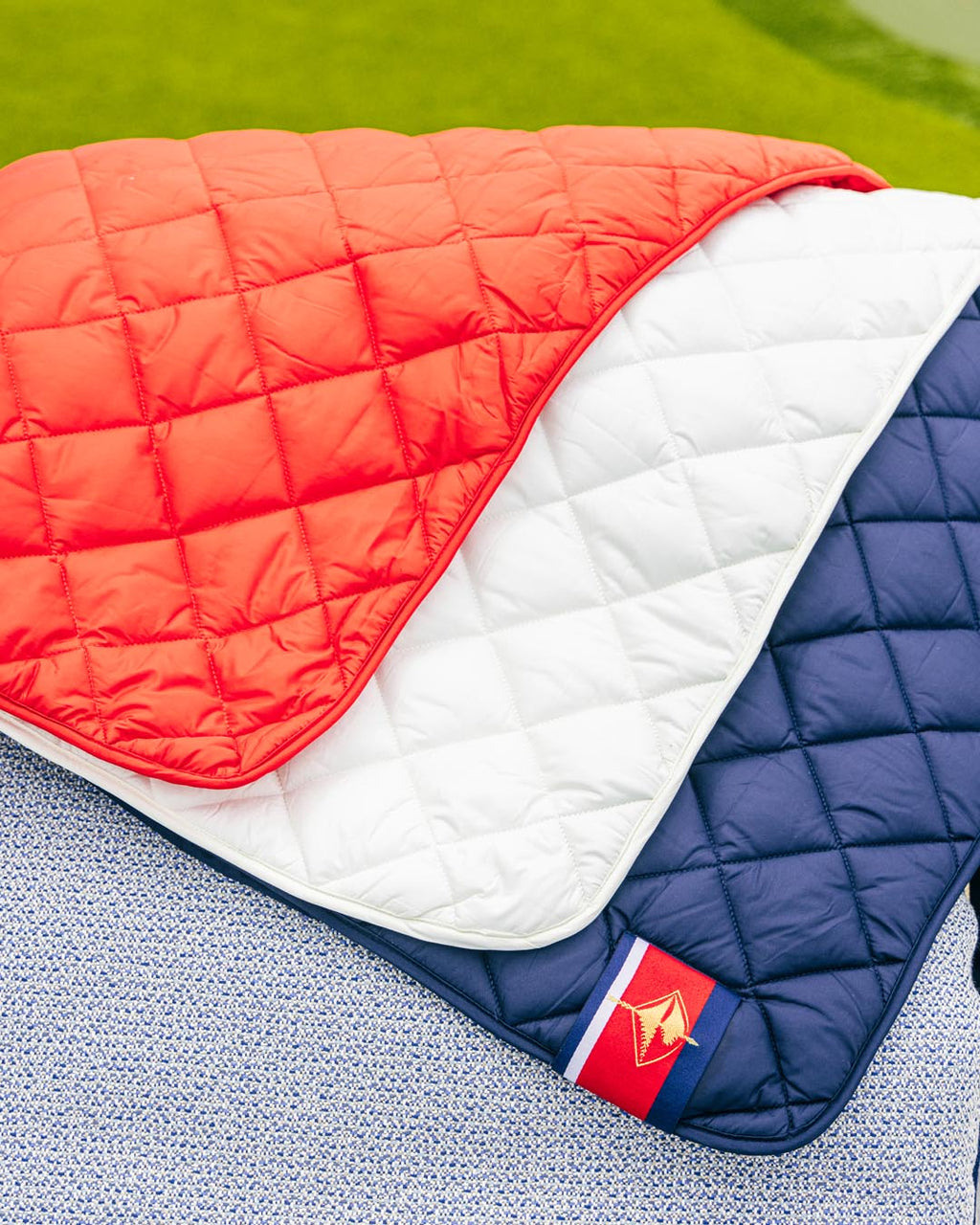 Waterproof puffer blanket with pockets, red and white quilted panels with navy trim