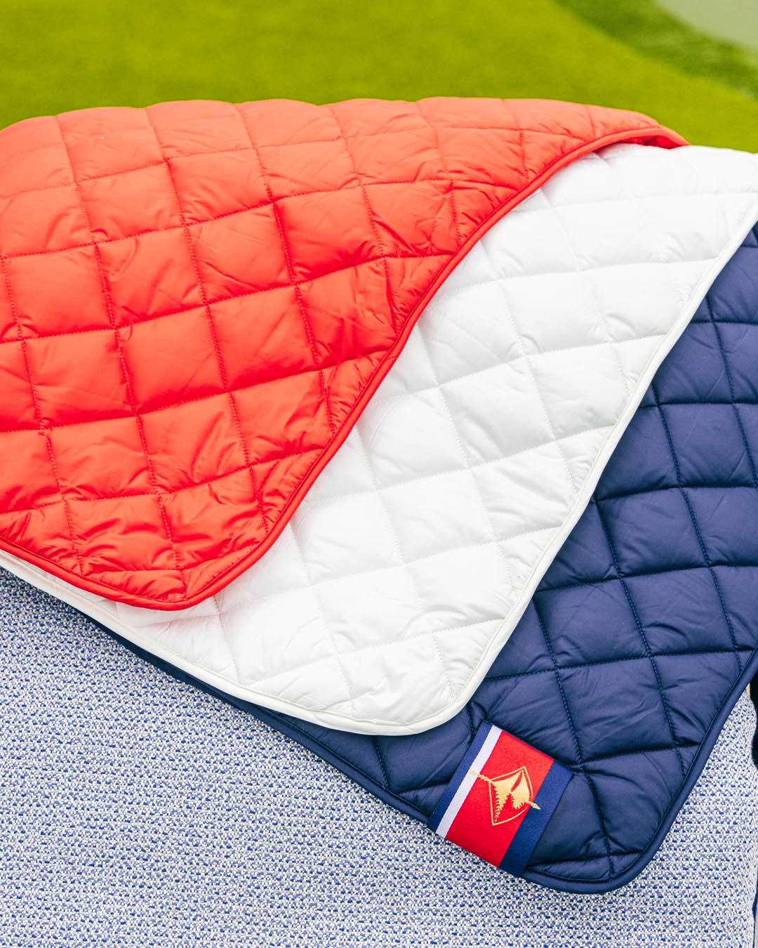 Waterproof puffer blanket with pockets, red and white quilted panels with navy trim