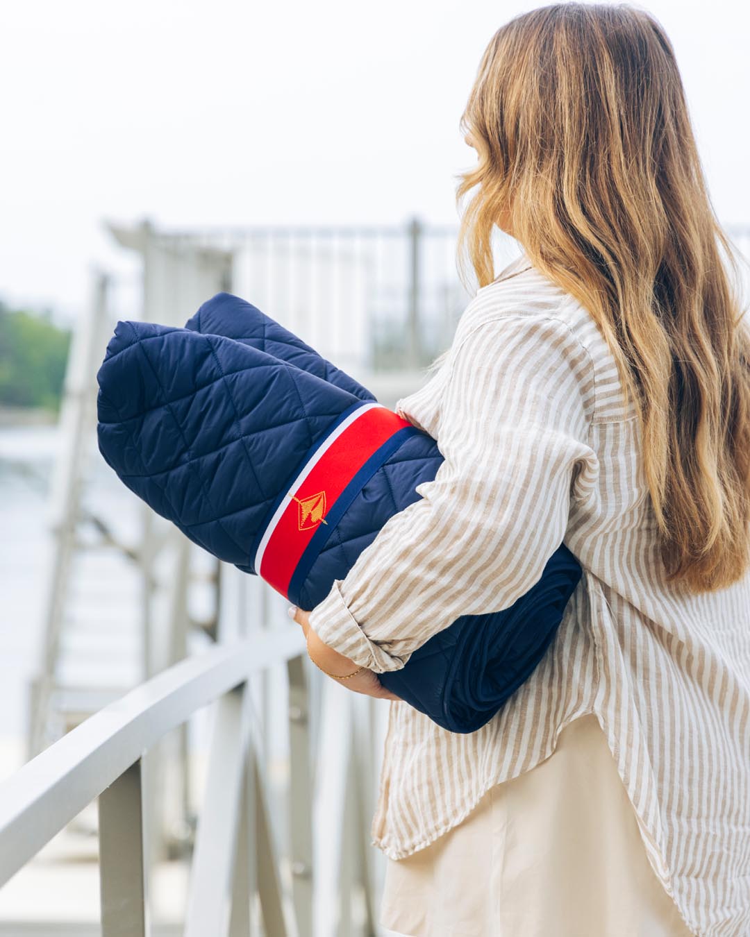 Navy quilted puffer blanket with pocket opening and stitched diamond pattern