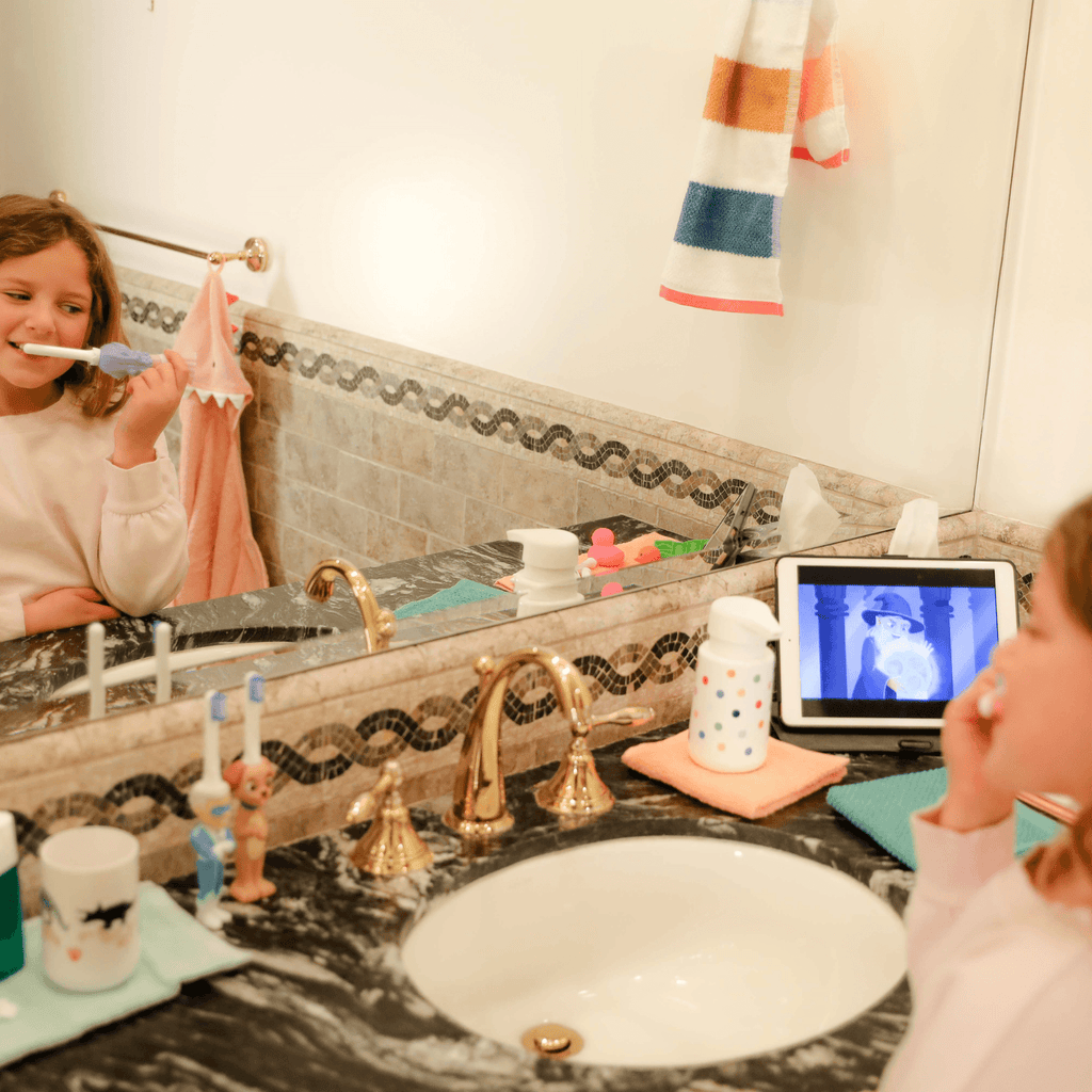 Child brushing with kids toothbrush, white handle and pink bristles at sink