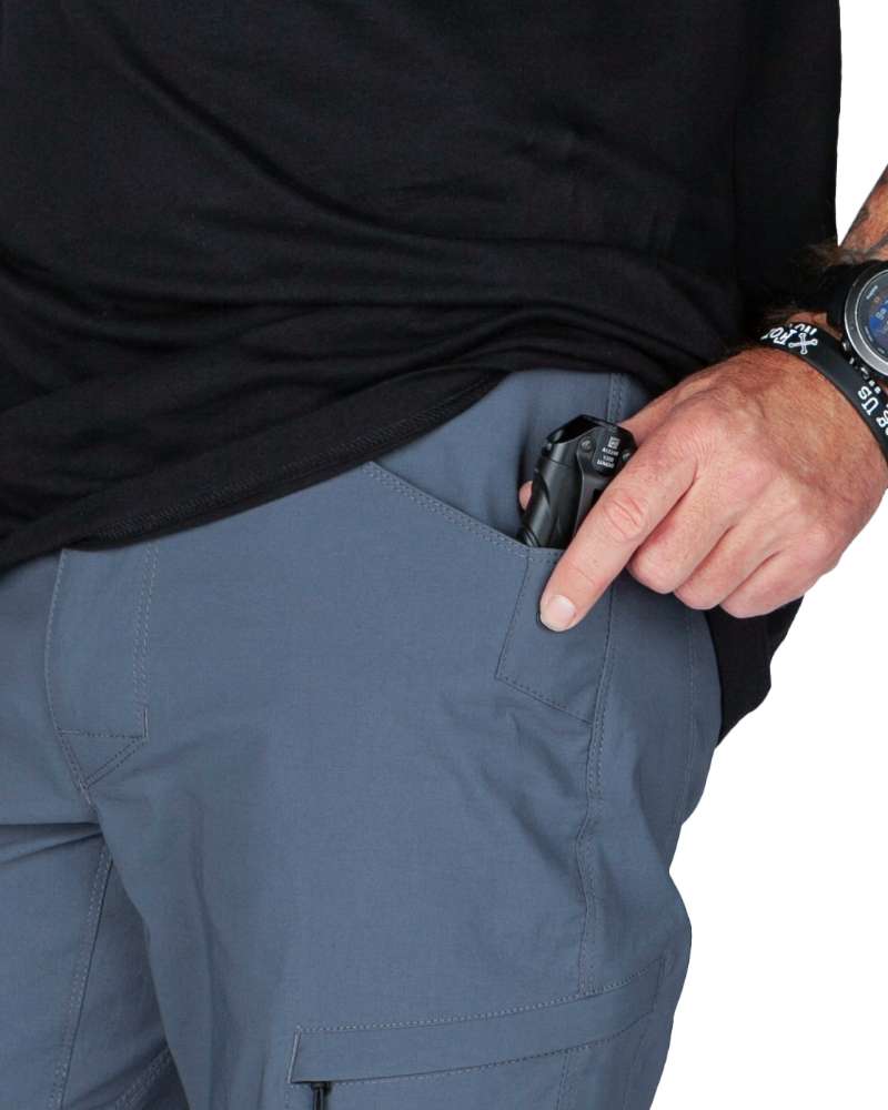 Gray-blue cargo pocket detail with hand near a small zip compartment