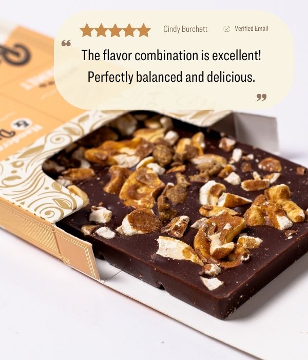 Dark chocolate bark in open package, topped with coconut caramel and cashews