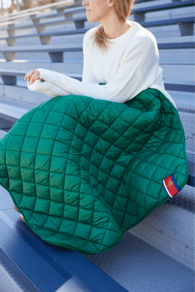 Green quilted waterproof puffer blanket with stitched diamond pattern, folded