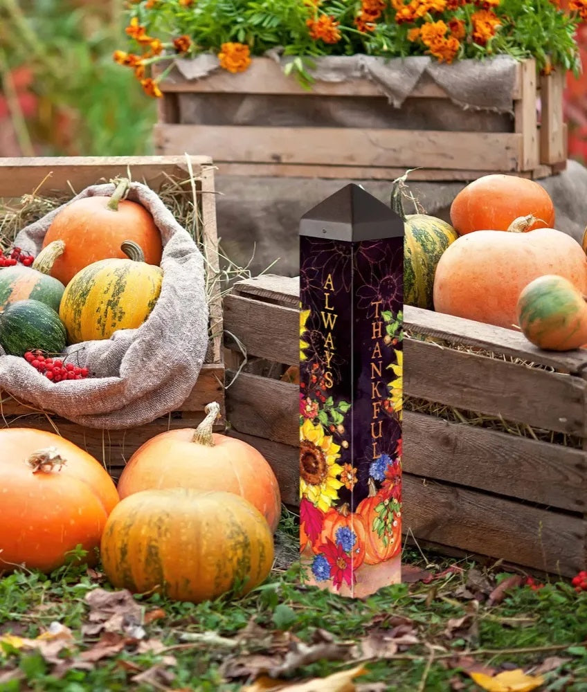 Outdoor fall art pole with pumpkin bouquet floral graphics, standing near pumpkins