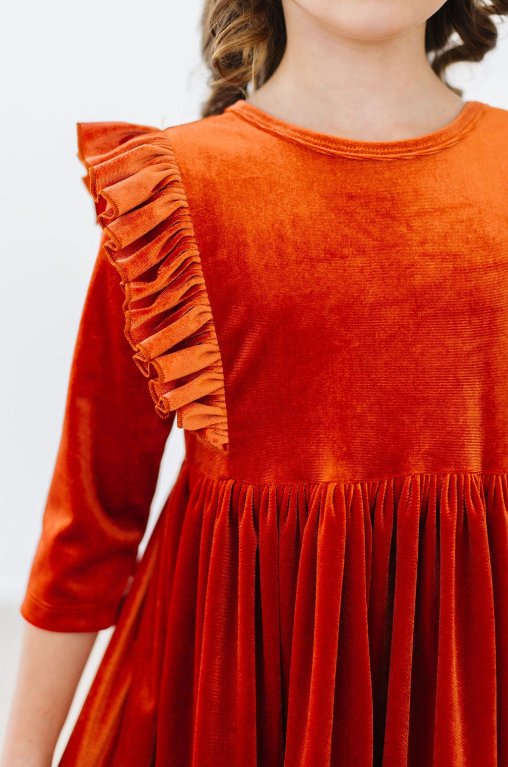 Orange velvet dress with ruffled sleeve trim and gathered pleated skirt