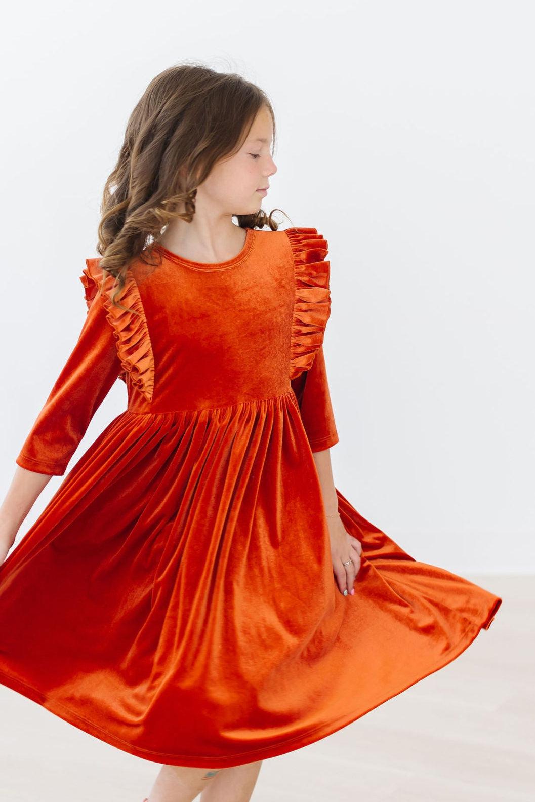 Burnt orange velvet dress with ruffled sleeves, gathered waist, and flared skirt