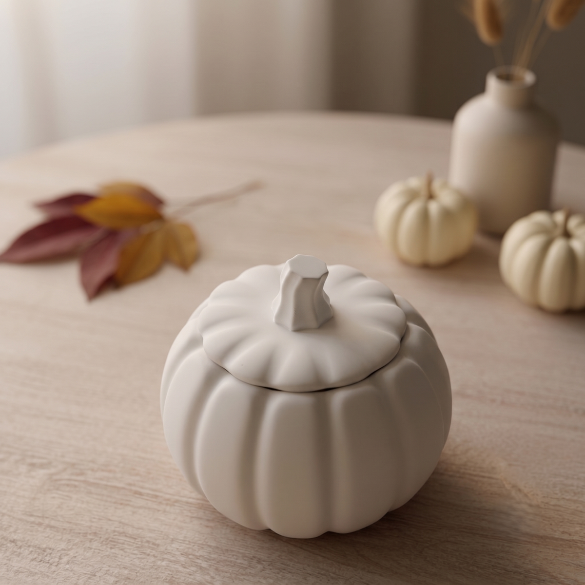 White pumpkin-shaped candle with ridged sides and removable lid, unlit
