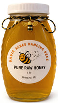 Amber glass honey jar with white lid and ribbon tie, labeled pure raw honey 1 lb