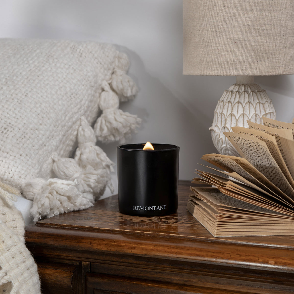 Black wood wick candle with small flame and Remontant label on dark jar