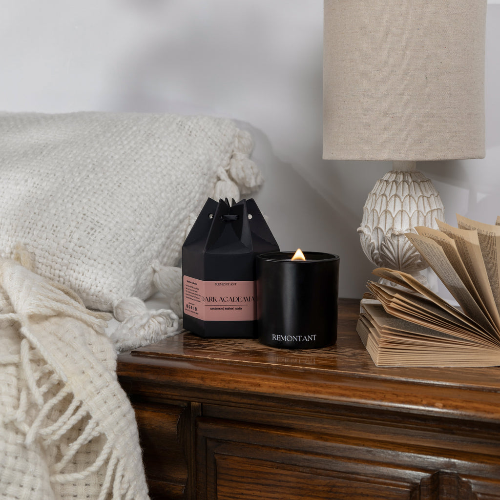 Black glass wood wick candle jar with lit flame and Remontant label