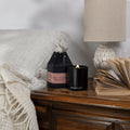 Black glass wood wick candle jar with lit flame and Remontant label