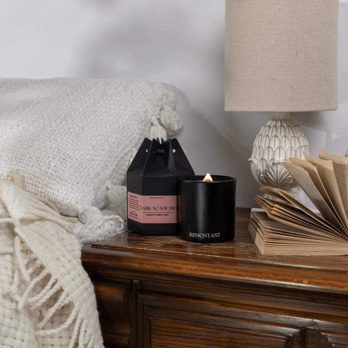 Black glass wood wick candle jar with lit flame and Remontant label