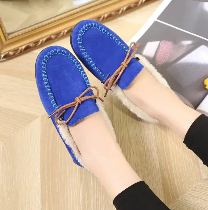 Women's blue plush slip-on moccasin flats with tan lace ties and fuzzy lining