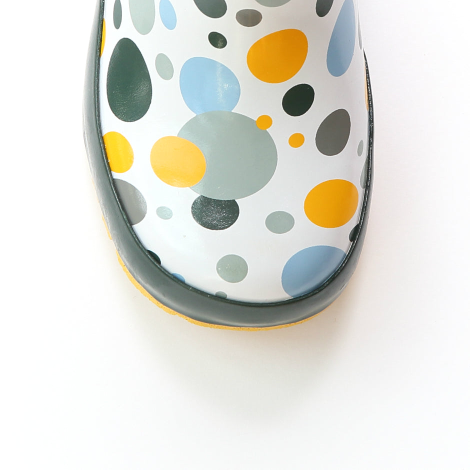 Close-up of white rain boot toe with multicolor dot print and dark green trim