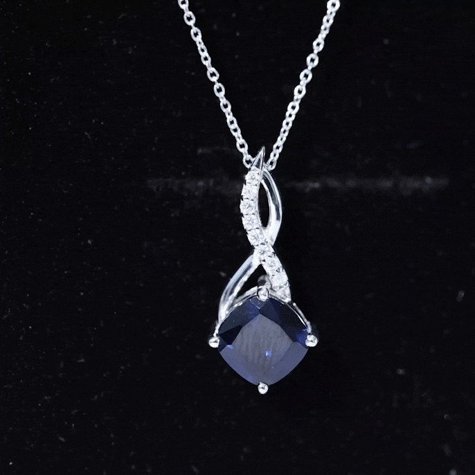 Silver infinity pendant necklace with dark blue cushion sapphire drop and diamond accents