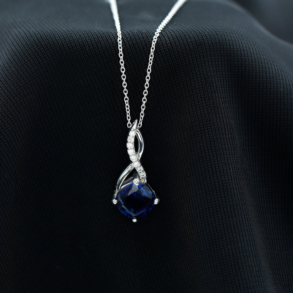 Silver infinity pendant necklace with dark blue cushion sapphire and diamond halo detail