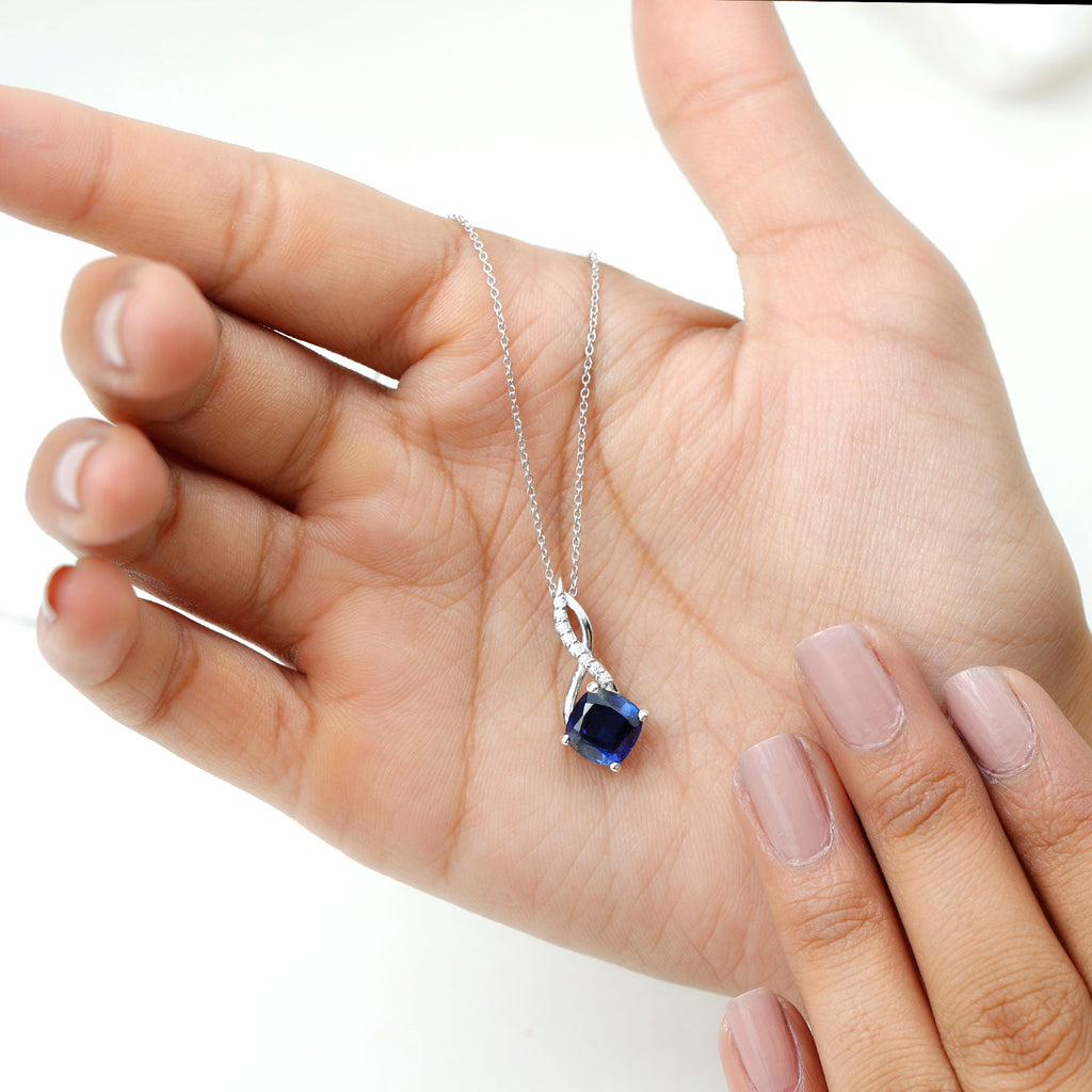 Close-up of cushion-cut blue sapphire infinity pendant on silver-tone chain
