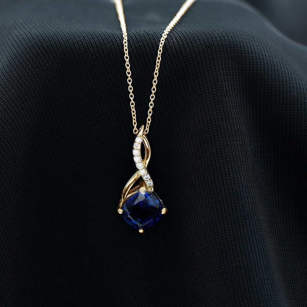 Gold infinity pendant necklace featuring a dark blue cushion sapphire and diamond details