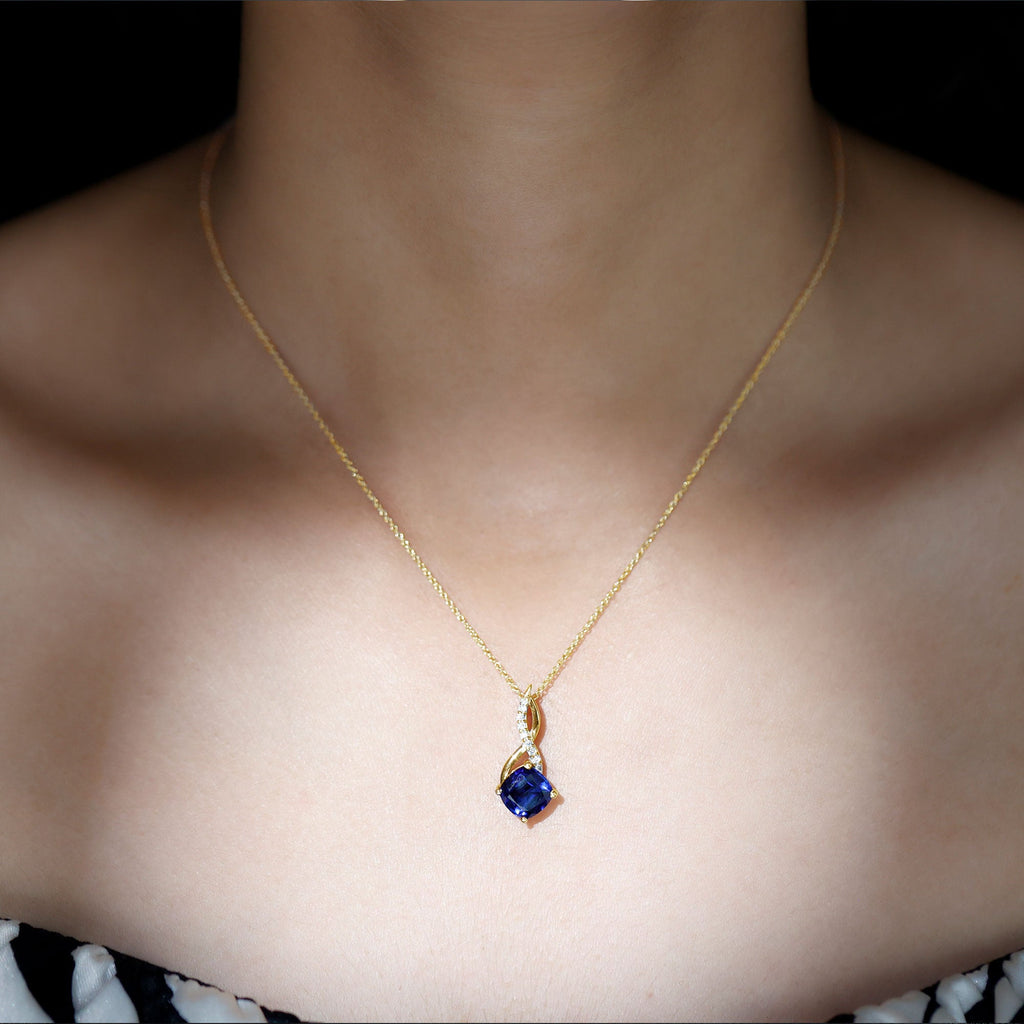 Gold necklace with small blue cushion sapphire pendant and thin infinity-style setting