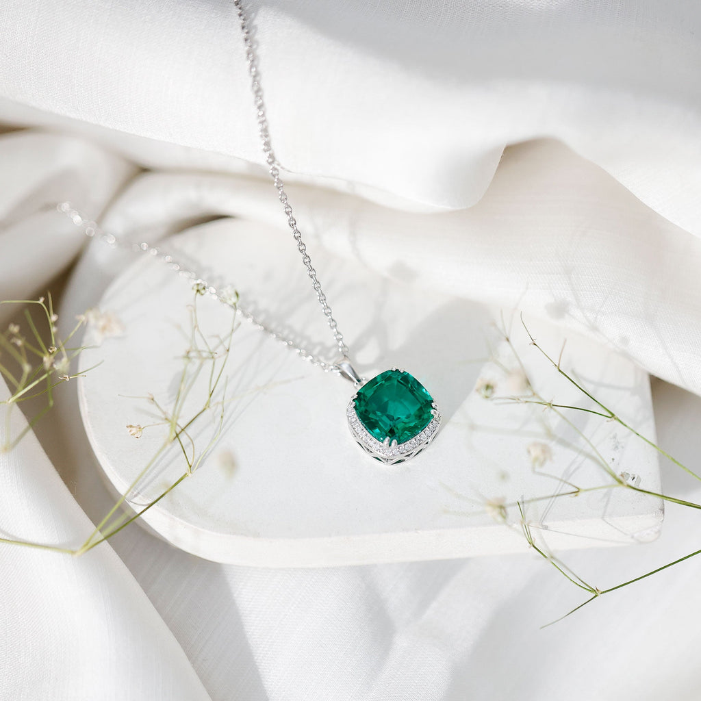 Silver-toned necklace with cushion-cut green emerald pendant and small diamond halo