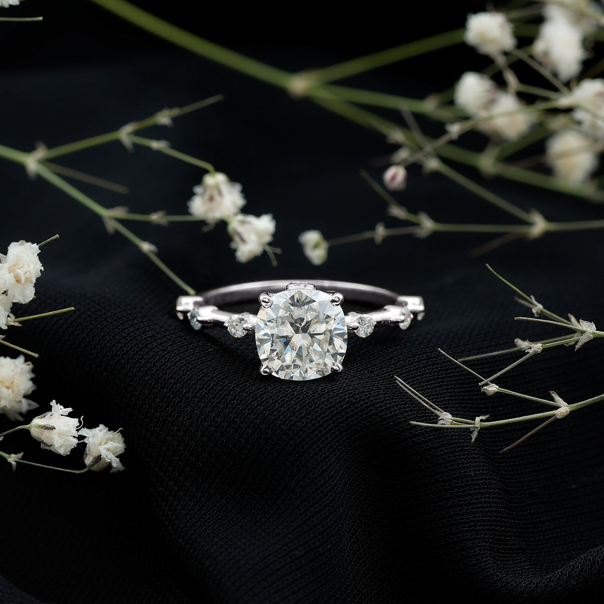 White metal cushion-cut diamond solitaire ring with small side diamonds, prong setting